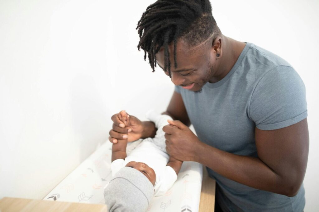 A loving father engaging with his newborn baby indoors, fostering a bond.