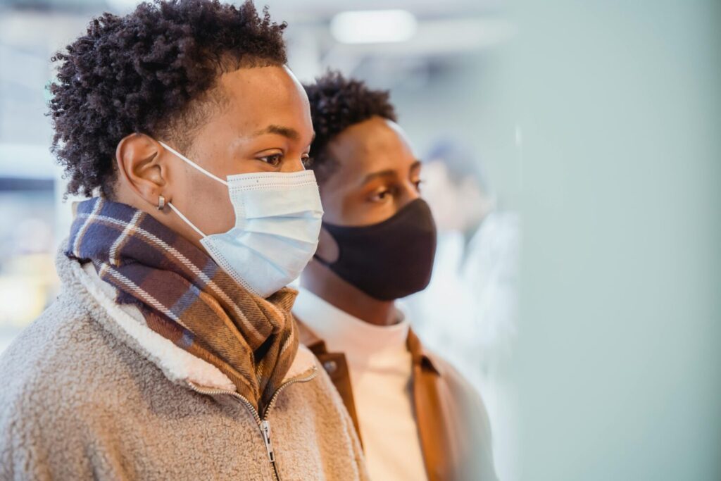 Two men wearing protective masks, focusing on their surroundings with serious expressions.
