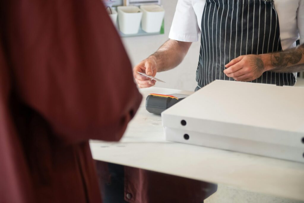 Chef receiving card payment for pizza order in a restaurant.